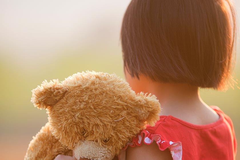 Looking at back of young girl with teddy bear